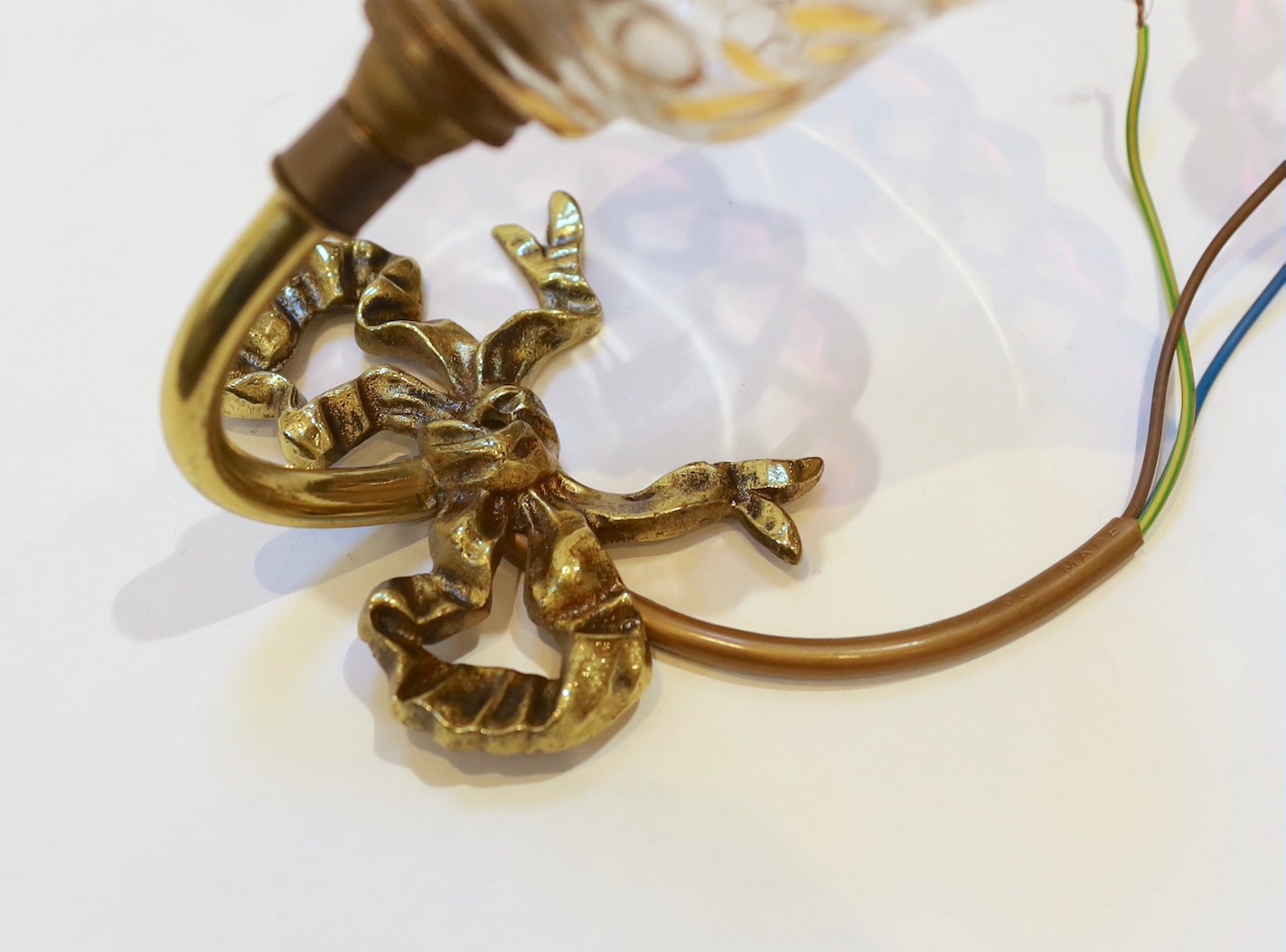 A pair of 1920s brass wall lights with frosted flame glass shades and a pair of brass ribbon back wall lights with lustre shades, height 14cm & height 12cm